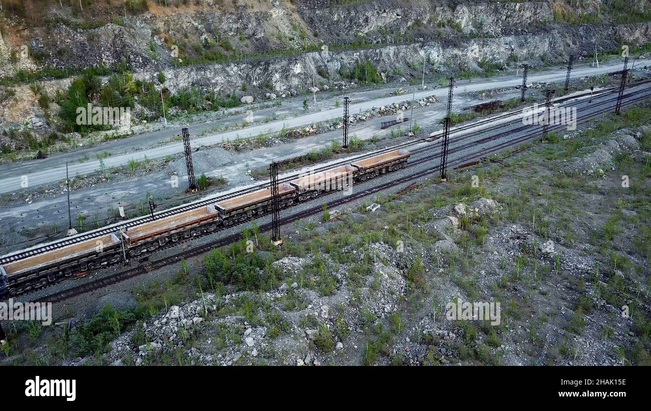 Die Diesellokomotive schiebt einen mit Schutt gefüllten Muldenkipper im Hintergrund eines Steinbruchs für den Kalksteinabbau. Stockfoto