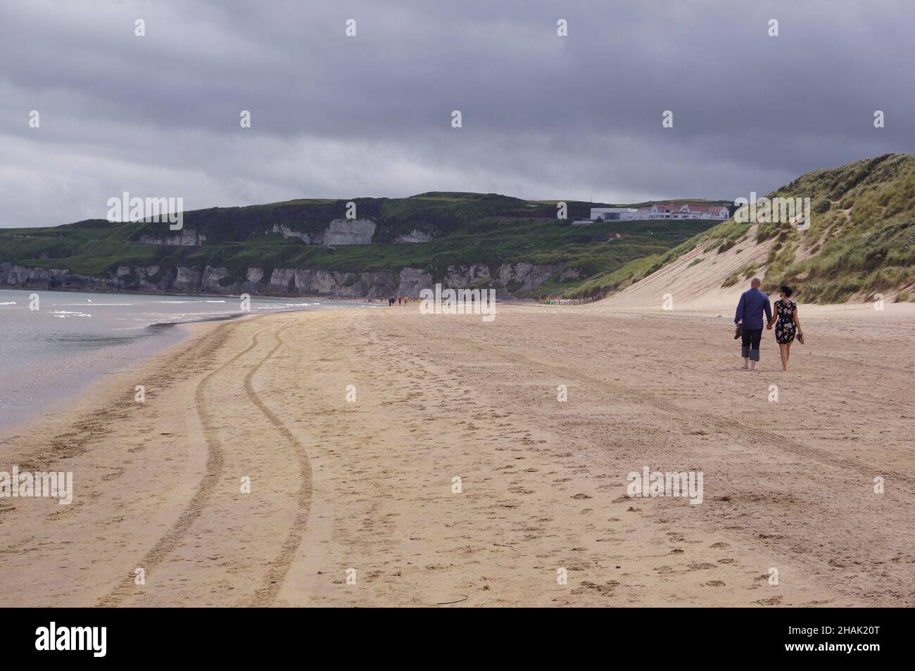 Ein Paar, das an der Küste von Whiterocks Beach in Portrush, Grafschaft Antrim, Nordirland, entlang geht Stockfoto