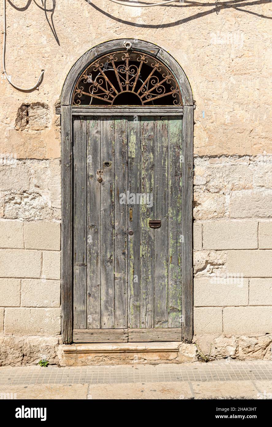 Alte Holztür des typischen antiken mediterranen Steinhauses in Sizilien. Stockfoto