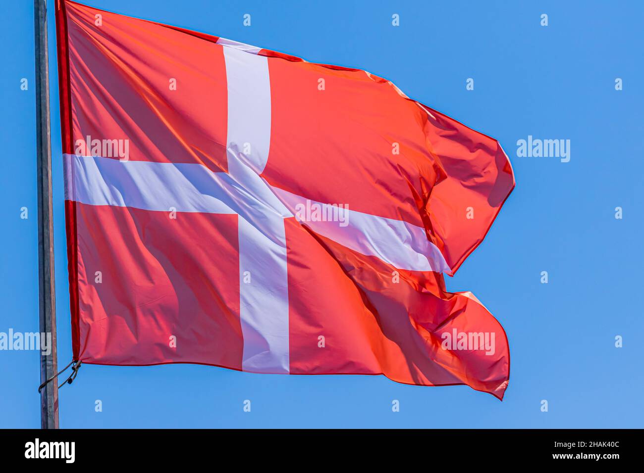Dänische Nationalflagge winkt auf blauem Himmel Hintergrund. Königreich Dänemark, DK Stockfoto