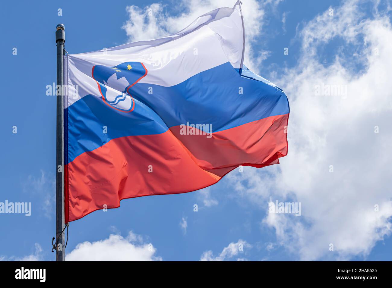 Slowenische Nationalflagge winkt auf blauem Himmel Hintergrund. Republik Slowenien, SL Stockfoto