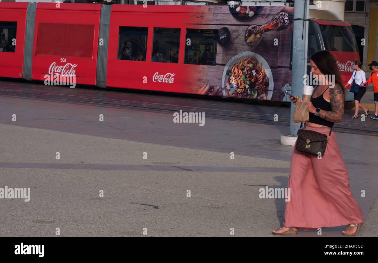 LISBOA, PORTUGAL - 20. Okt 2021: Lisboa, Portugal,20,2021. Oktober: Praca do Comrcio Eine junge Frau überprüfte ihr Handy, während eine Straßenbahn hinter sich war Stockfoto