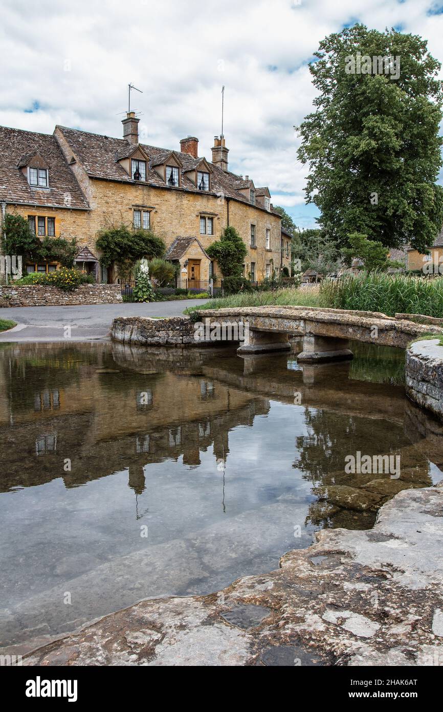 Spiegelung eines Hauses und einer Steinbrücke, Lower Slaughter, Gloucestershire, England, Vereinigtes Königreich. Das Dorf liegt an beiden Ufern des Flusses Eye Stockfoto