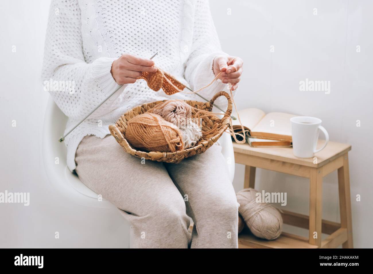 Eine Frau mittleren Alters beschäftigt sich mit häuslicher Handarbeit Stricken, Stricken mit Fäden. Home-Aktivität Hobby in der Freizeit Stockfoto