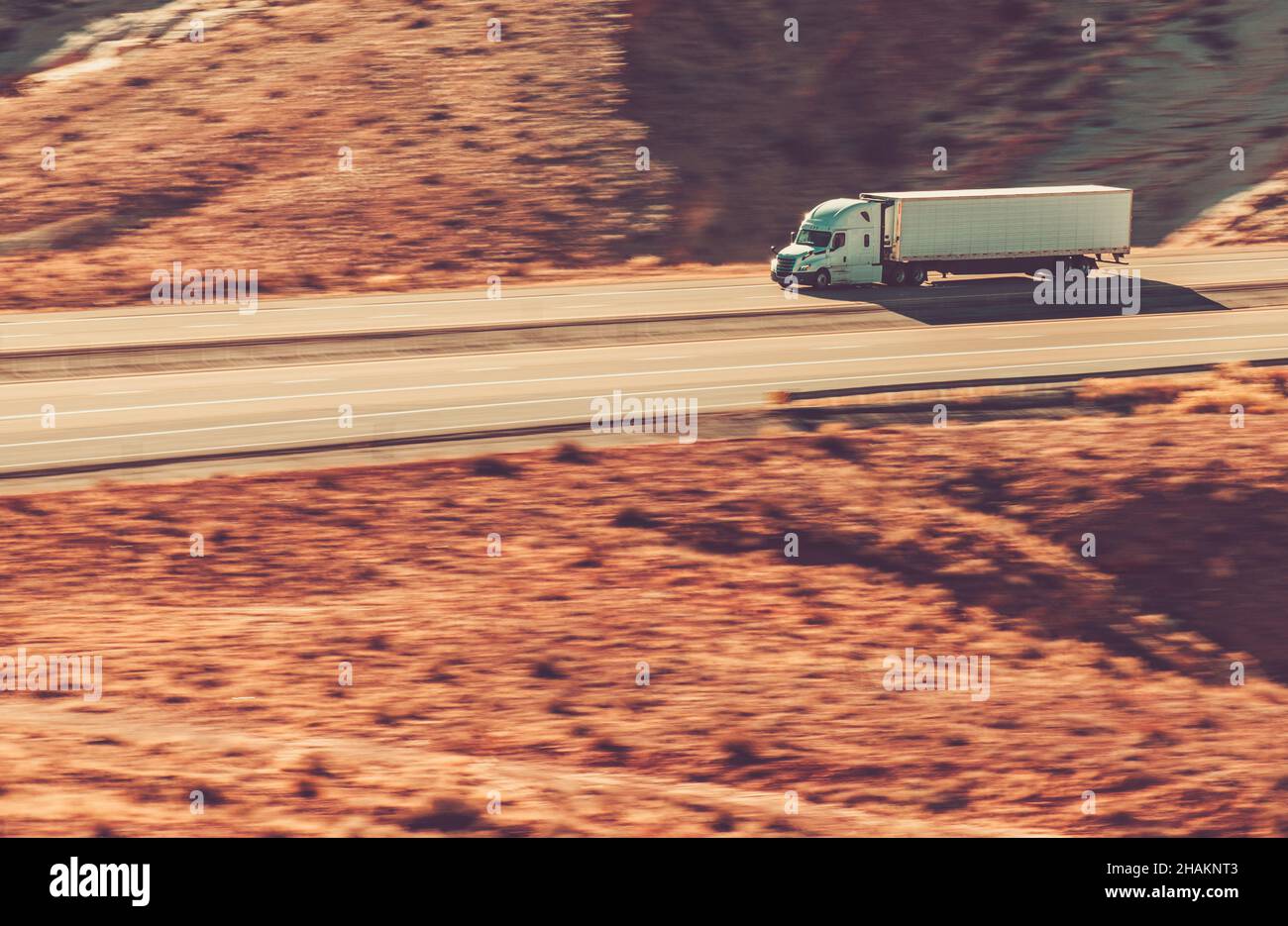 Speeding Modern Semi Trailer Truck auf der Interstate Highway 70, Utah State USA. Felsformationen Landschaft. Stockfoto