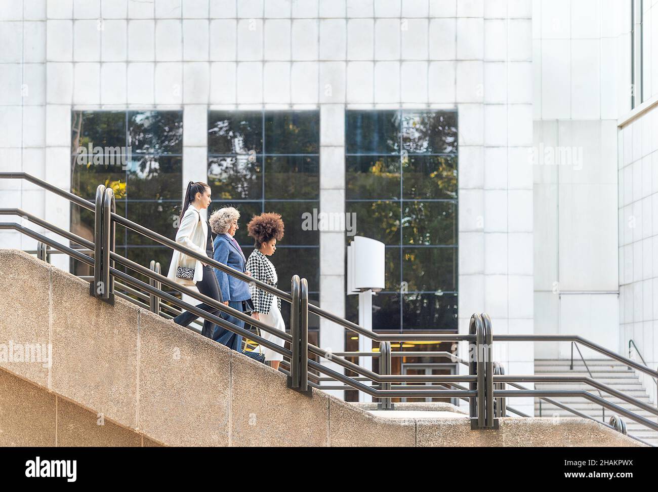 Seitenansicht von drei Frauen, die eine Treppe hinuntersteigen Stockfoto