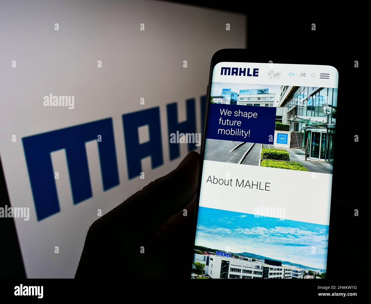 Person, die Mobiltelefon mit der Webseite des deutschen Automobilzulieferers MAHLE GmbH auf dem Bildschirm vor dem Logo hält. Konzentrieren Sie sich auf die Mitte des Telefondisplays. Stockfoto
