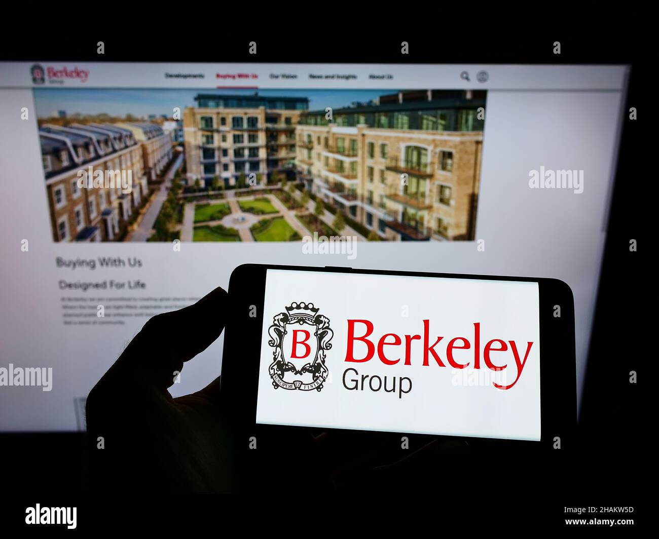 Person, die ein Mobiltelefon mit dem Logo des britischen Unternehmens The Berkeley Group Holdings plc auf dem Bildschirm vor der Webseite hält. Konzentrieren Sie sich auf die Telefonanzeige. Stockfoto