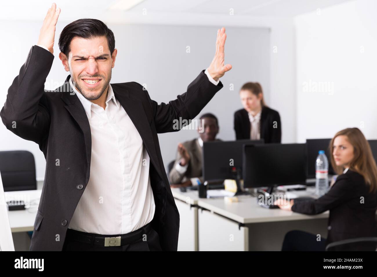 Junger Geschäftsmann, der im Hintergrund mit Kollegen im Büro steht Stockfoto