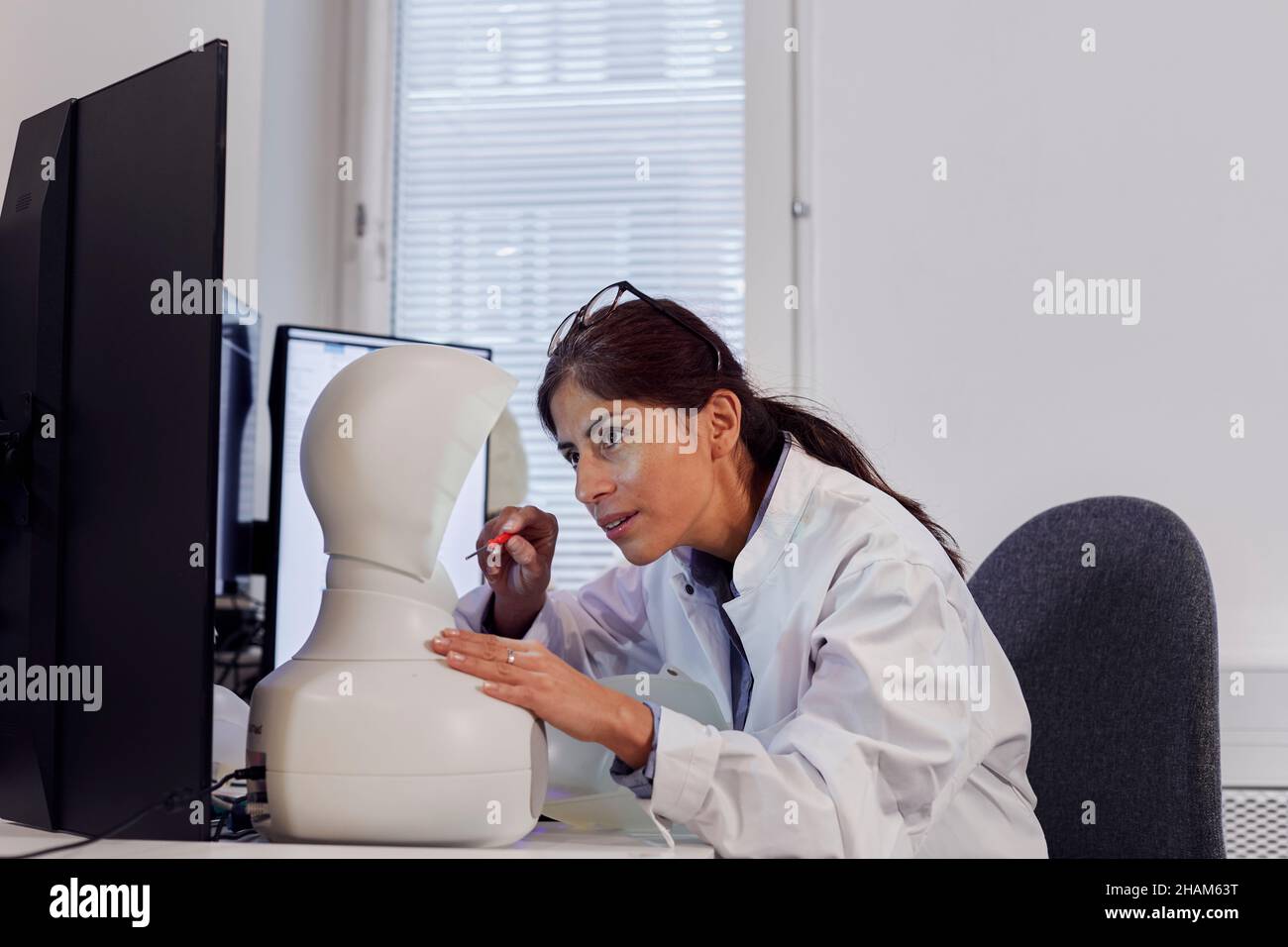 Ingenieurin baut Roboter am Arbeitsplatz Stockfoto