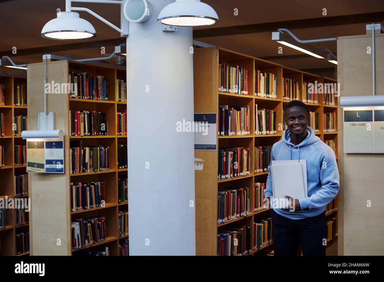 Junger männlicher Student in der Bibliothek Stockfoto