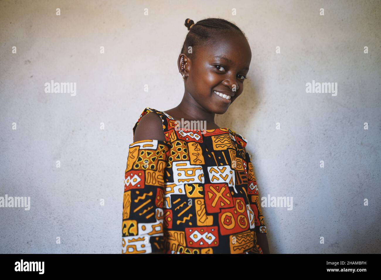 Nettes schwarzes afrikanisches Mädchen in schönen traditionellen Kleid stehen gegen weiße weiße leere Wand Hintergrund Stockfoto