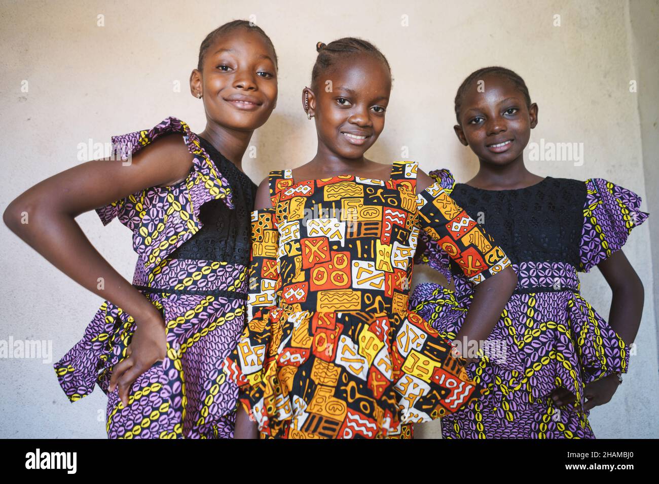 Nahaufnahme drei junge schöne afrikanische Mädchen stehen zusammen und blicken selbstbewusst in die Kamera und lächeln in traditionellem malischem Kleid. Einheit und kultureller Tauchgang Stockfoto