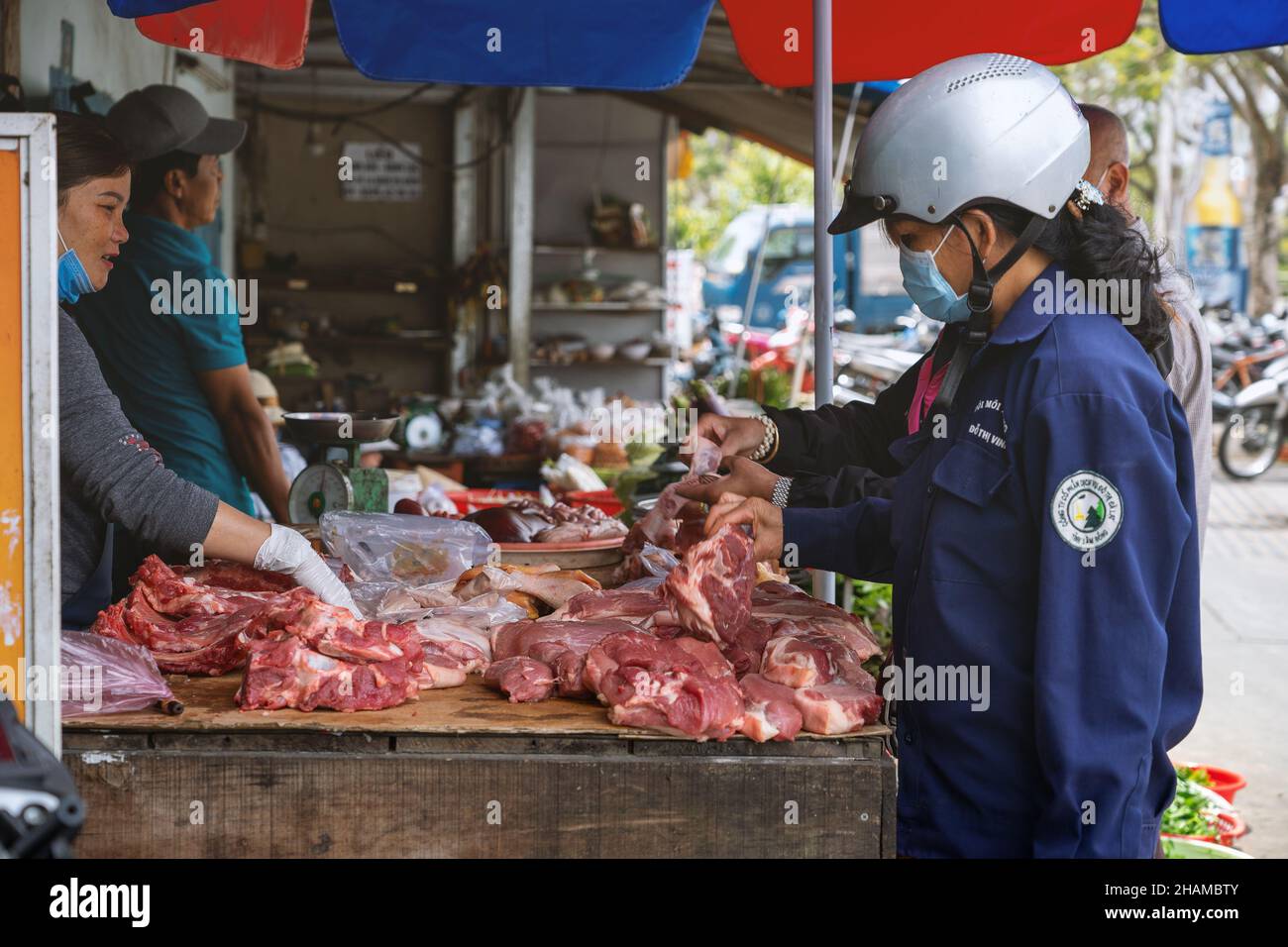 In der Freilufttheke einer Metzgerin auf dem Straßenmarkt. Die Käuferin wählt das Fleisch. Da Lat, Vietnam: 2021-05-08 Stockfoto