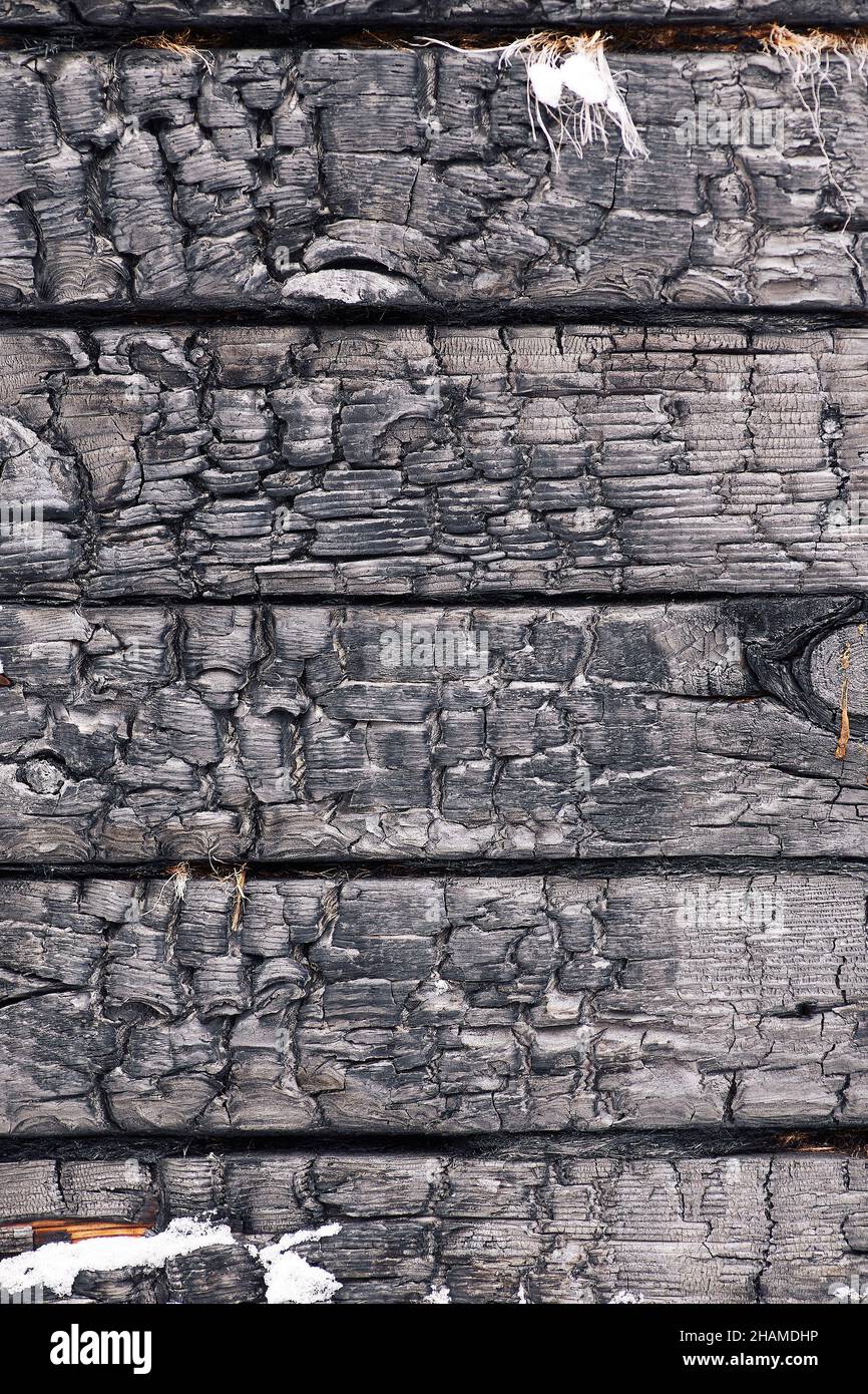 Schwarz strukturierter Vollformat-Hintergrund mit verkohlten Holzschreibtischen mit Schnee und Rissen Stockfoto