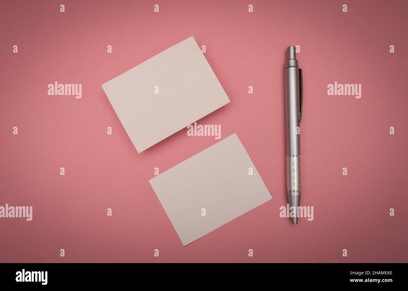 Leere Visitenkarte auf rosa Hintergrund mit einem Stift Stockfoto