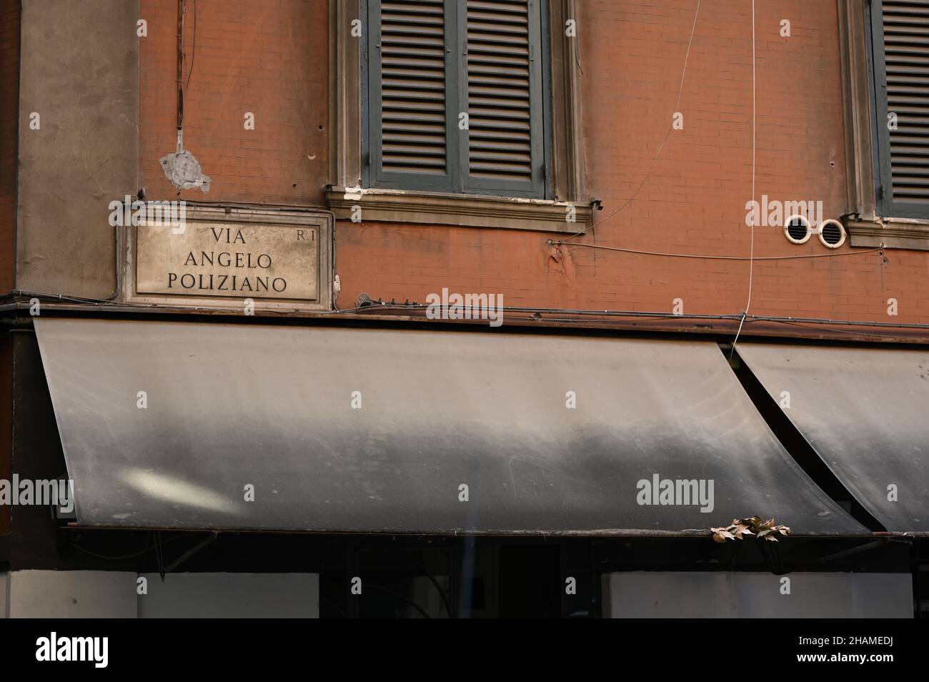 Fassade eines alten orangefarbenen Wandgebäudes mit einem Text 'VIA ANGELO POLIZIANO' in Rom, Italien Stockfoto