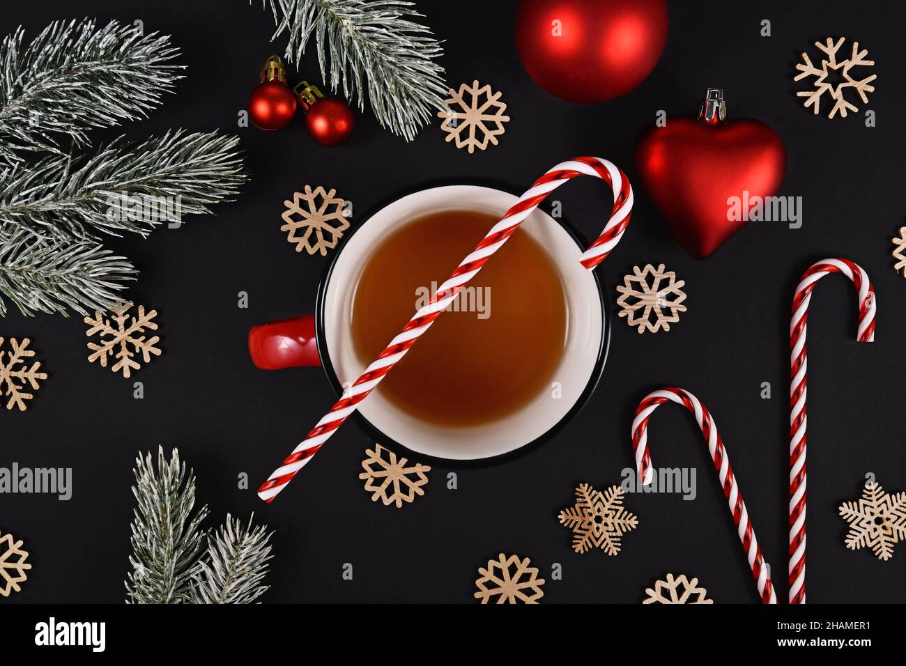 Tasse Tee mit Candy Cane und weihnachtlicher Dekoration auf schwarzem Hintergrund Stockfoto