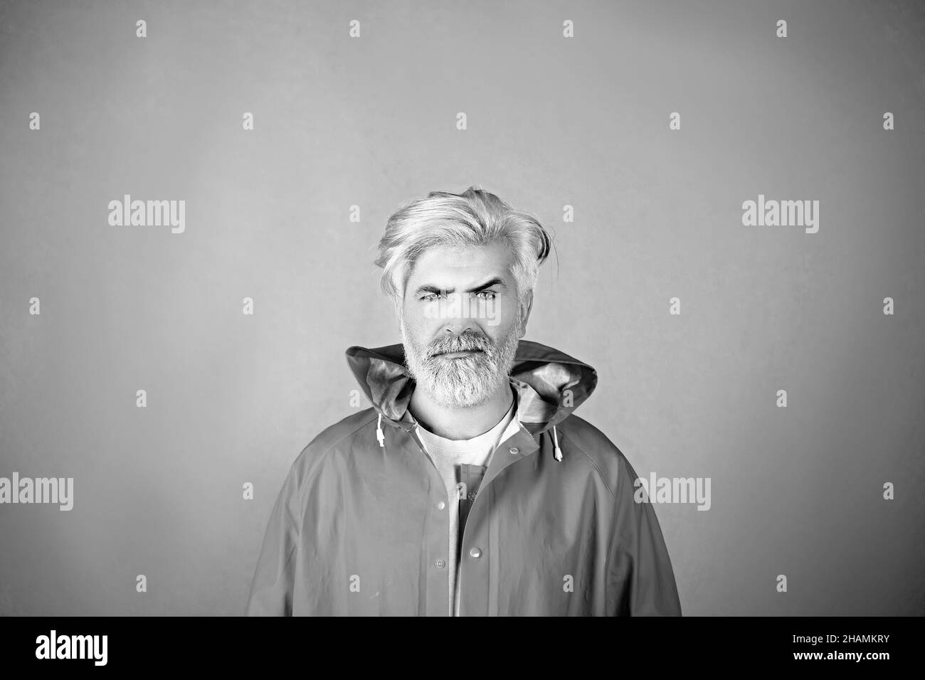 Porträt eines reifen Mannes mit gelben Haaren in einem gelben Regenmantel isoliert auf gelbem Hintergrund. Stockfoto