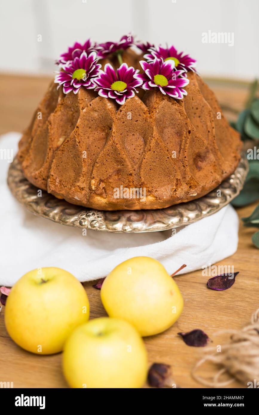 Stillleben mit einem Apfelkuchen mit Blumen und Küchenutensilien. Stockfoto