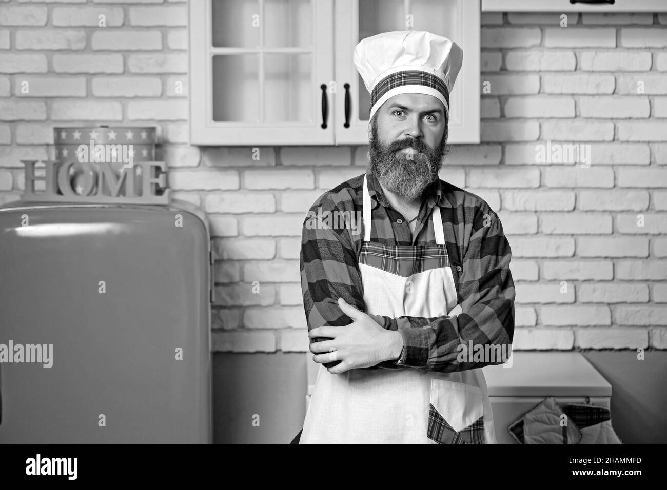 Ein junger bärtiger Mann, gekleidet in ein rotes Hemd und weiße Schürze. Stockfoto