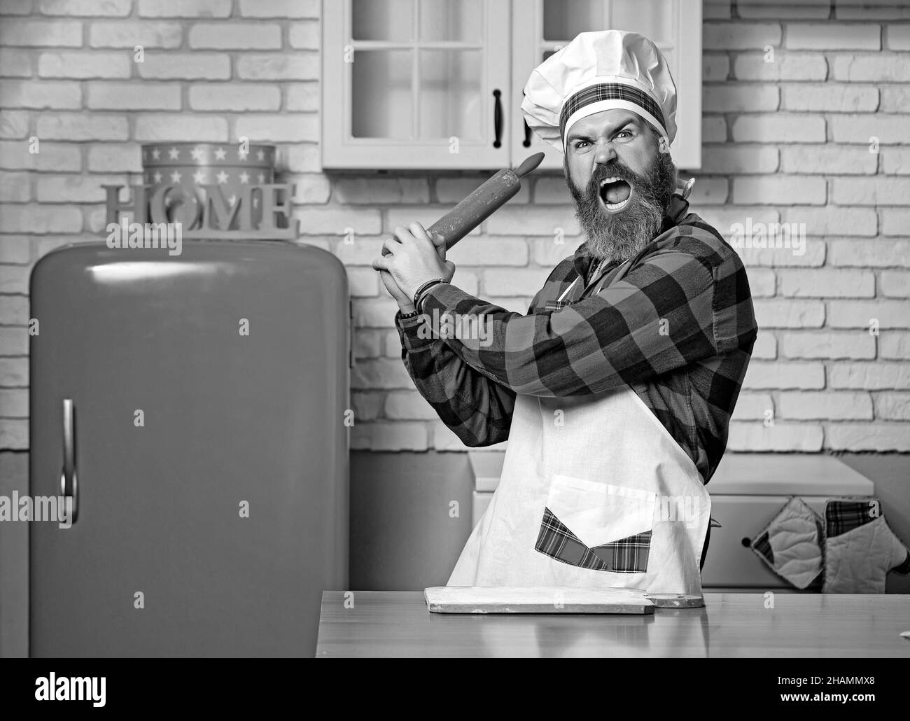 Junge bärtige Koch wütend oder hämmern auf jemanden in der Küche. Stockfoto