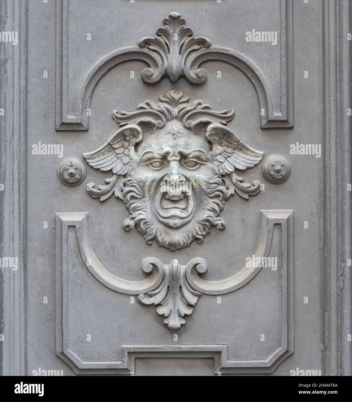 Schreiendes menschliches Gesicht mit Flügeln, mythologische Figur auf Palasttür geschnitzt Stockfoto