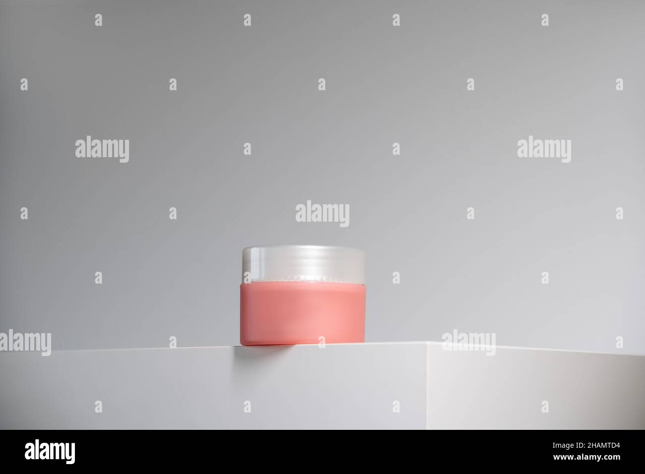 Zartrosa Cremetopf mit silbernem Deckel auf weißem Podium und Hintergrund. Moderner geometrischer Minimalismus in pflegeleichter Schönheit. Hero Shot Stockfoto