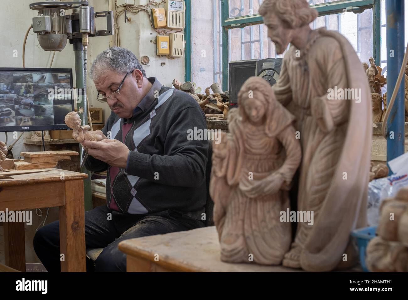 Bethlehem. 14th Dez 2021. Am 14. Dezember 2021 arbeitet ein Bildhauer an einer Olivenholzskulptur für das bevorstehende Weihnachtsfest in einer Werkstatt in der Stadt Bethlehem im Westjordanland. Quelle: Luay Sababa/Xinhua/Alamy Live News Stockfoto