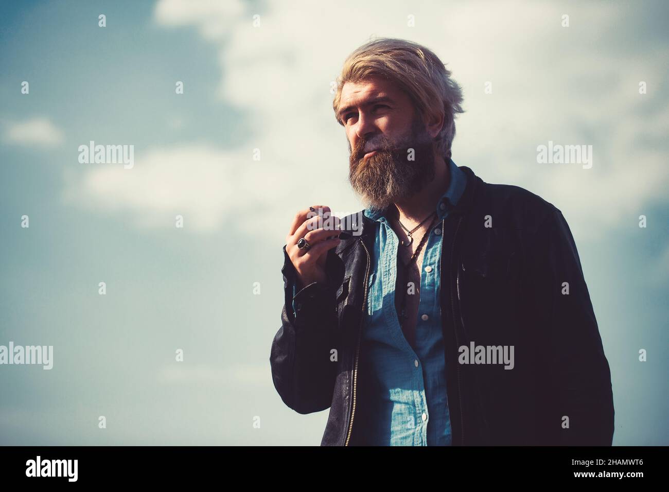 Bärtiger Hipster auf der Spitze des hohen Gebäudes mit Stadtbild im Hintergrund. Stockfoto