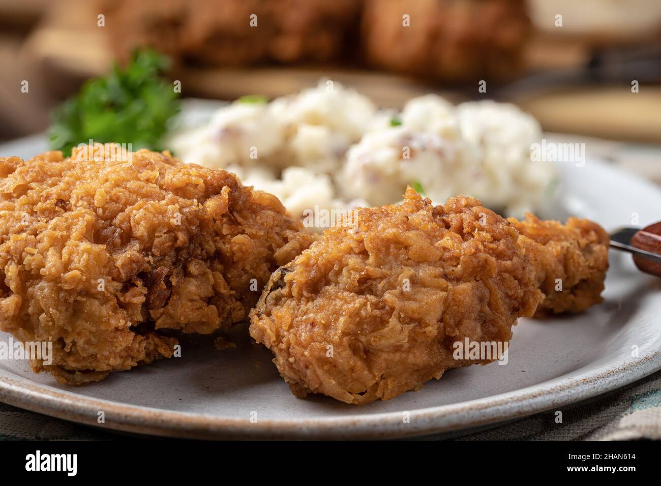 Nahaufnahme von knusprig gebratenem Hühnerschenkel und Oberschenkel-Abendessen mit Kartoffelpüree auf einem Teller Stockfoto