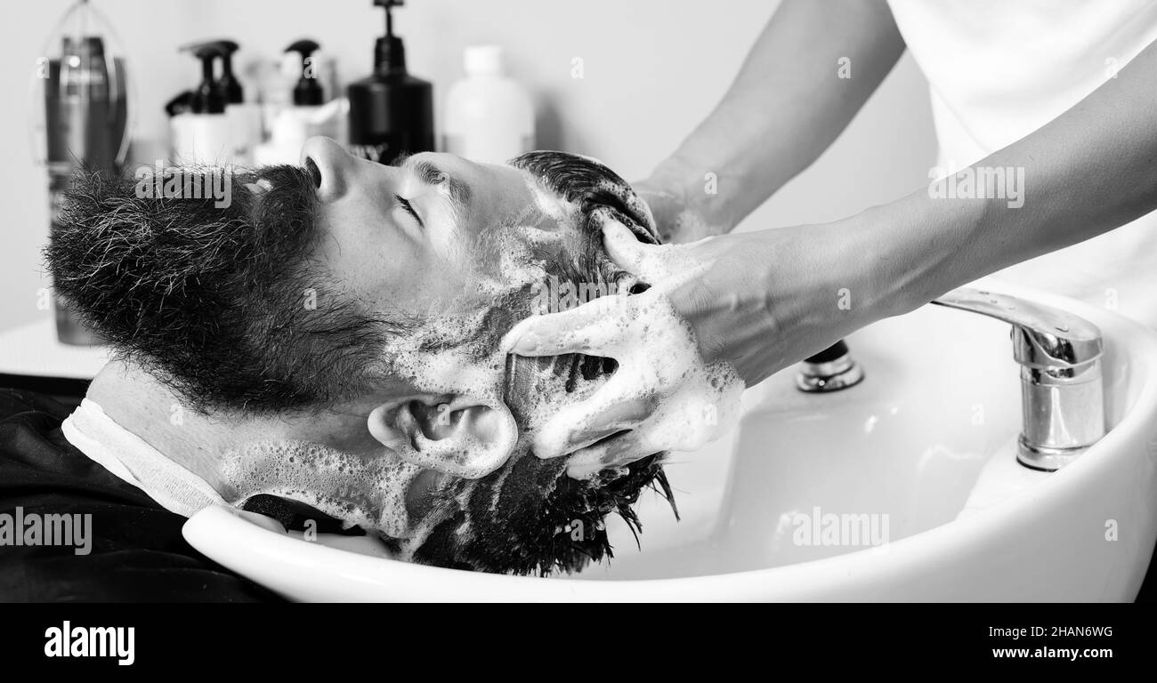 Nahaufnahme eines brutalen kaukasischen Mannes, der seine Haare im Friseursalon gewaschen hat. Friseur Waschkopf Client. Friseur bei der Arbeit. Stockfoto