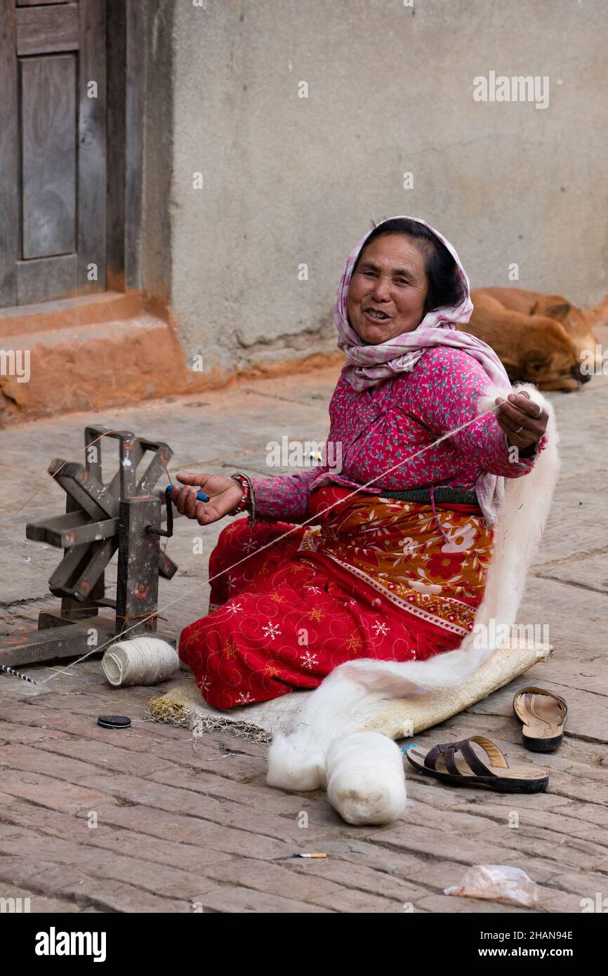 Eine nepalesische Frau, die im mittelalterlichen Dorf Khokana in Newari von Hand Wollfäden spinnt. Kathmandu Valley in Nepal. Stockfoto