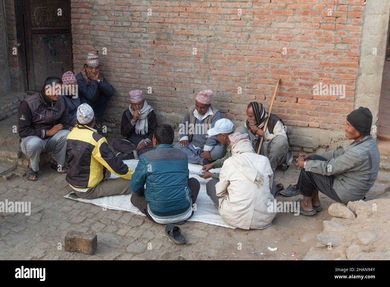 Nepalesische Männer spielen Karten auf der Straße im mittelalterlichen Newari-Dorf Khokana im Kathmandu-Tal von Nepal. Stockfoto