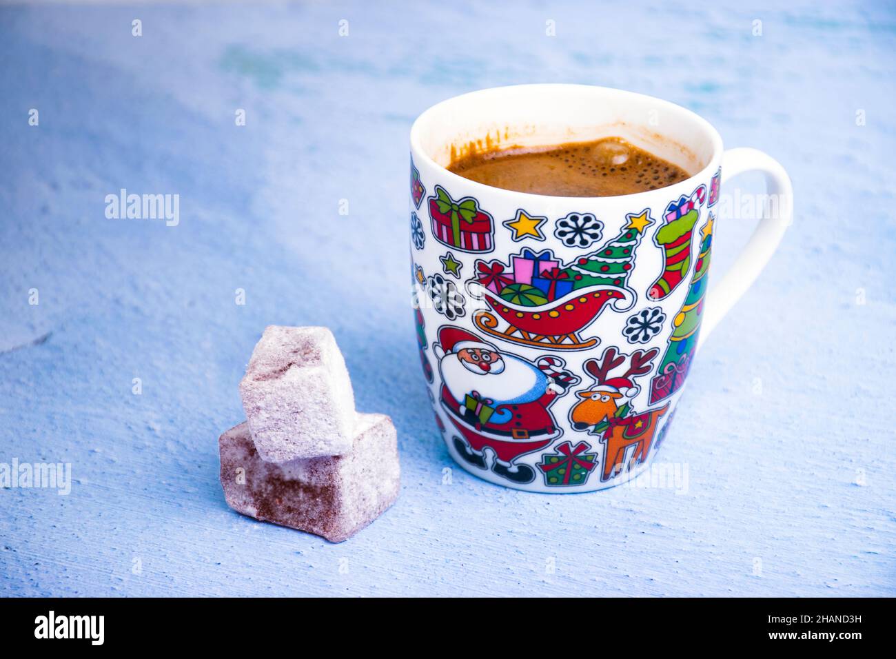 Schwarzer Kaffee in einer Tasse mit Neujahrsmotiv und türkischen Köstlichkeiten auf dem hellen Hintergrund. Stockfoto