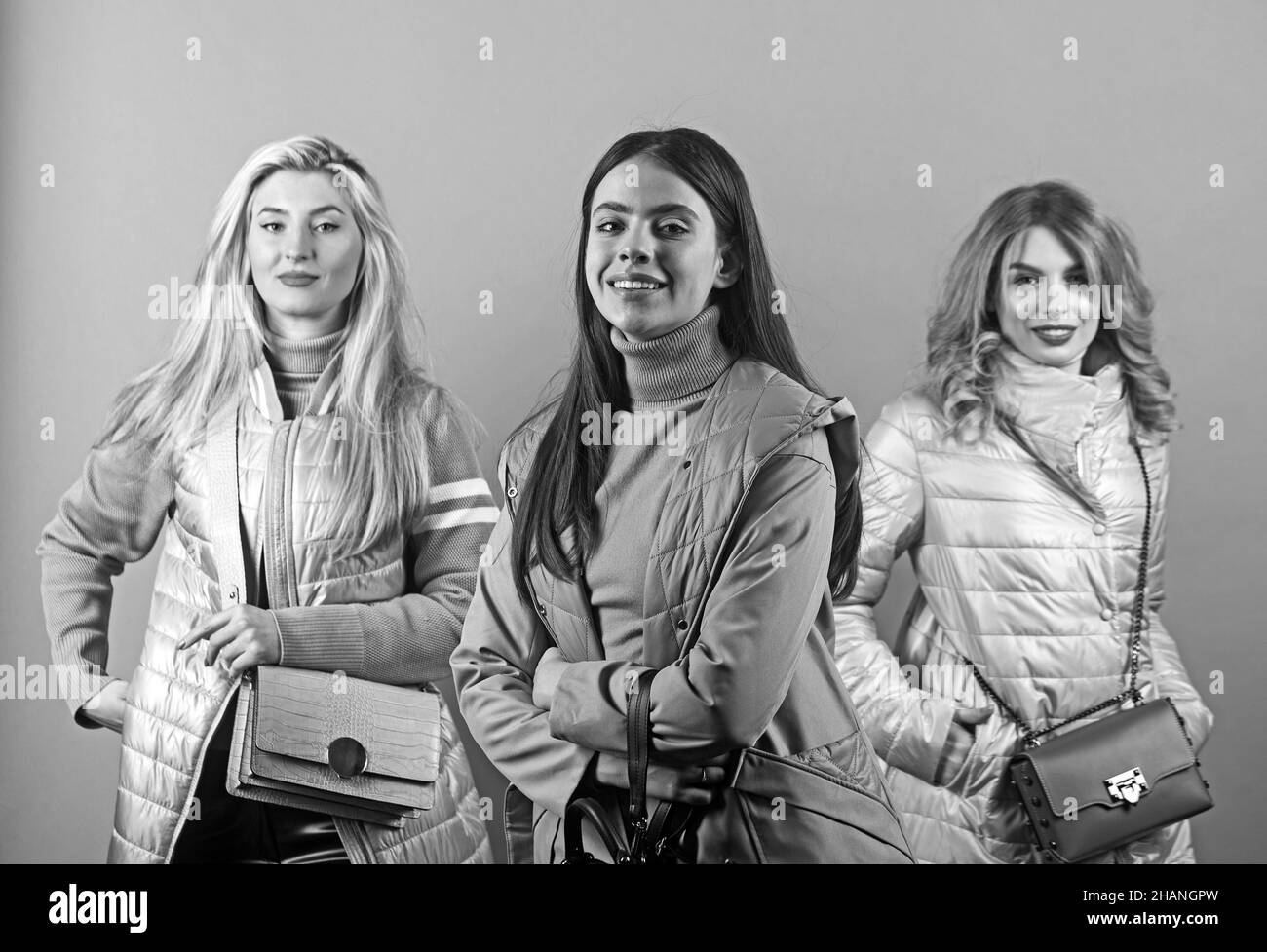 3 glückliche Casual Frauen posieren und lächeln, isoliert auf grauem Hintergrund. Stockfoto