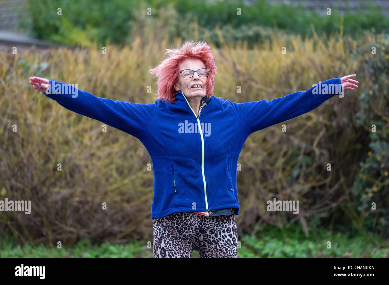 Ältere ältere Frau mit 80s Jahren, die im Winter draußen Sport macht und Sternsprünge macht. Alte Dame, die einen gesunden, aktiven Lebensstil hält. Stockfoto