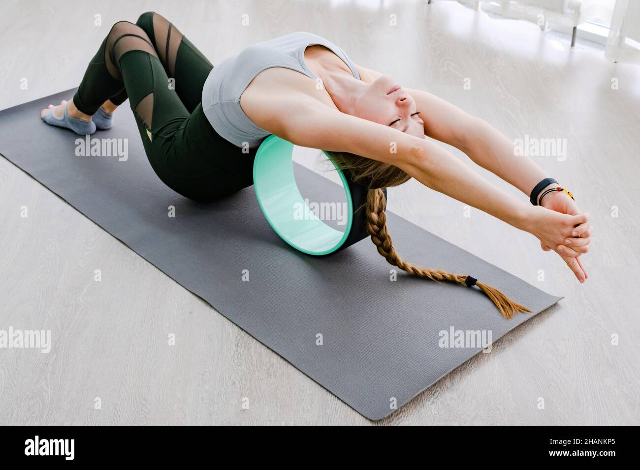 Professionelle Yoga-Dame zurück um Pilates Ring liegend auf grauem Hintergrund Boden und zeigt perfekte Fitness-Haltung Stockfoto