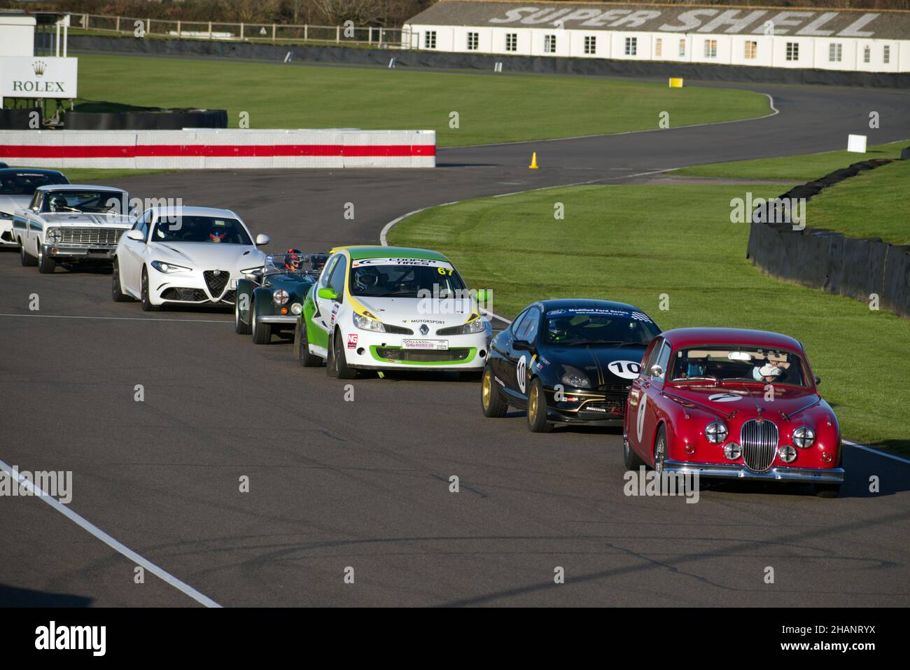 Ein Jaguar Mark 2 in Rot steht vor dem Start für eine Reihe von Oldtimern und Sprints, darunter ein Ford Puma, Morgan, Ford Falcon und ein Tesla-Modell. Stockfoto