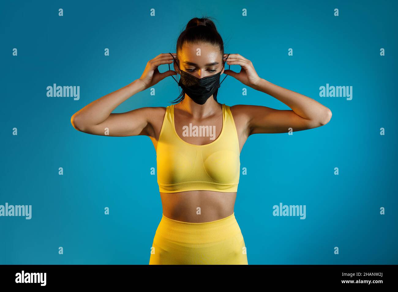 Sportliche Frau Setzt Auf Gesichtsmaske Stehen Auf Blauem Hintergrund Stockfoto