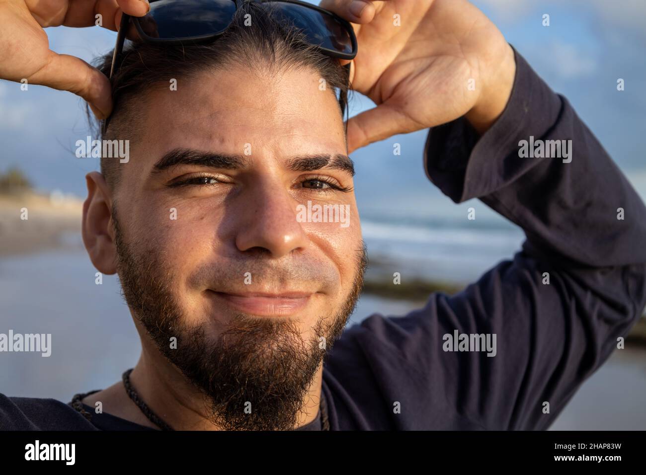 Junger Mann von Hipster oder Hippie Auftritt mit glücklichen Gesicht am Strand Stockfoto