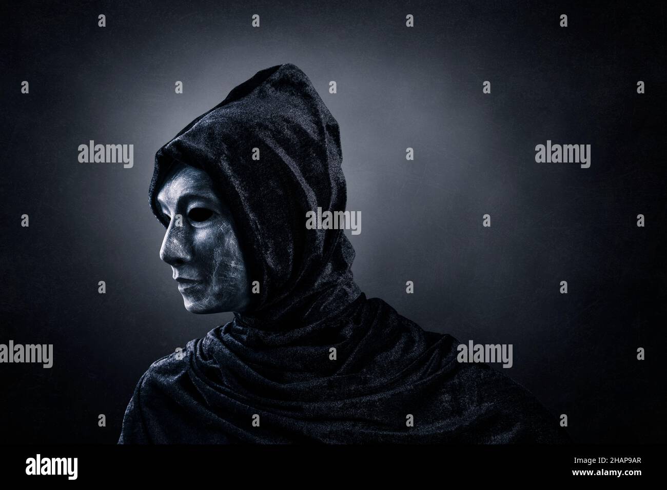 Gruselige Figur mit Kapuzenumhang im Dunkeln Stockfoto