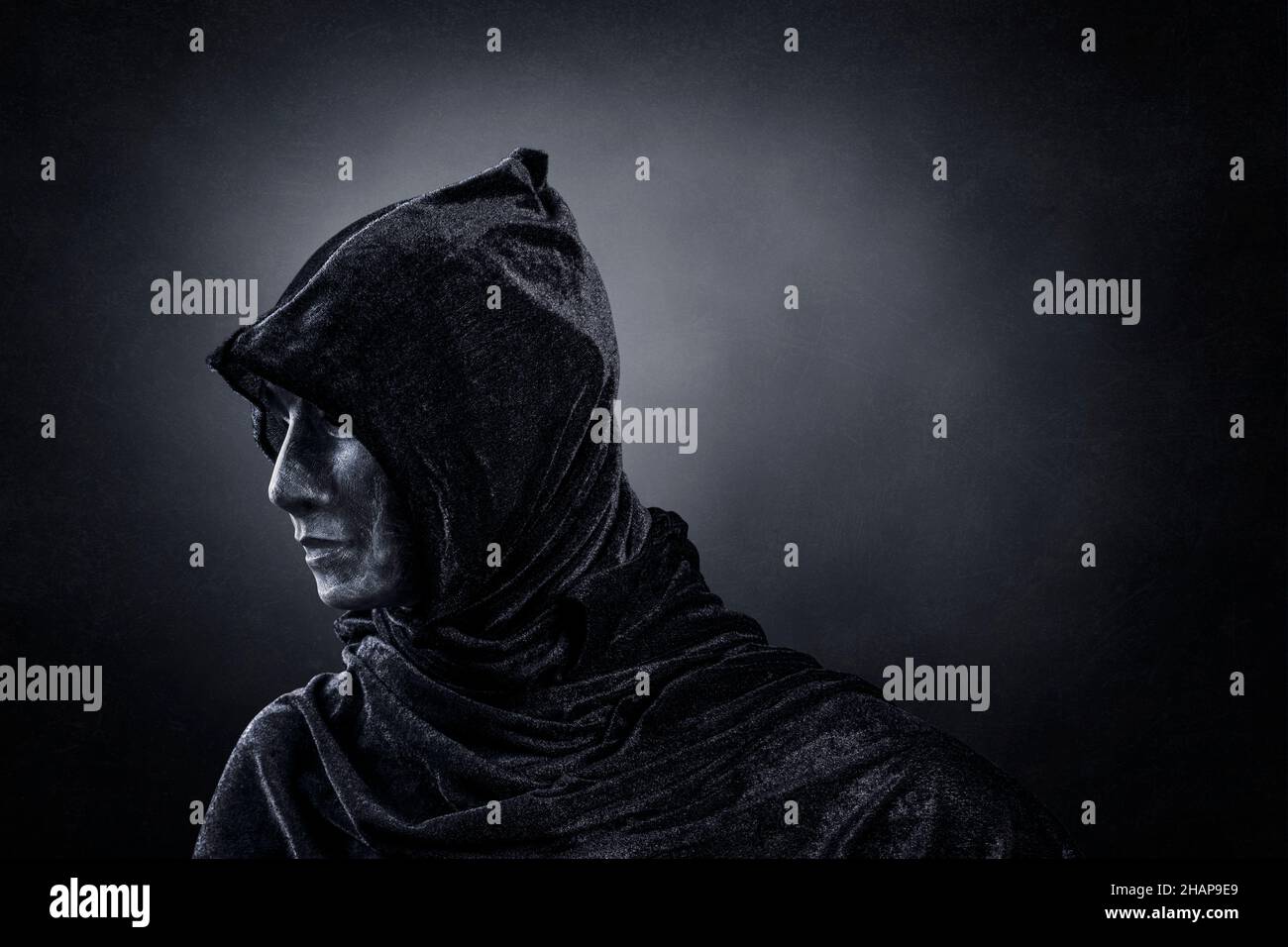 Gruselige Figur mit Kapuzenumhang im Dunkeln Stockfoto