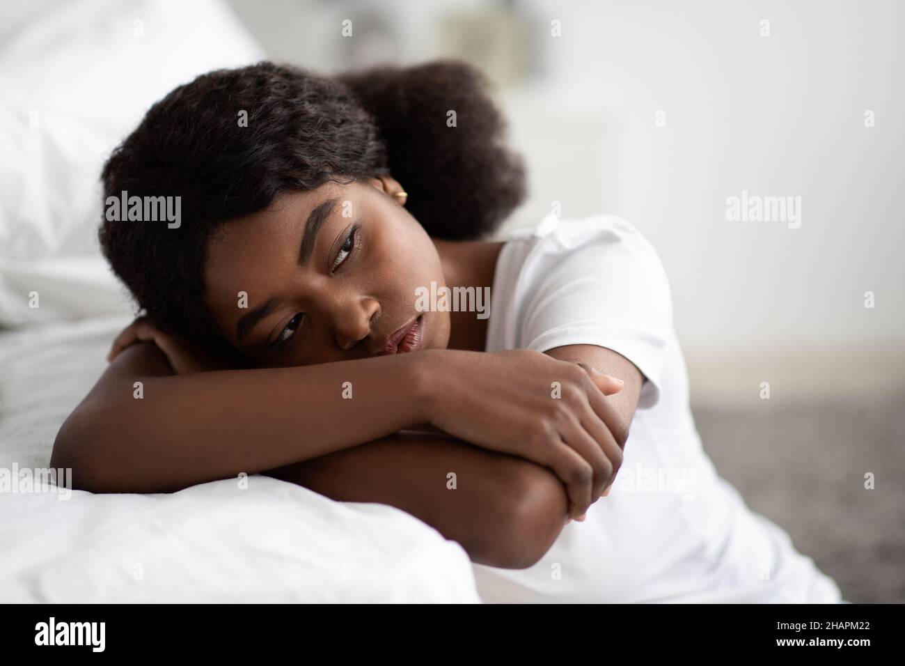 Depressive afroamerikanische Frau, die zu Hause am Bett sitzt, Nahaufnahme Stockfoto