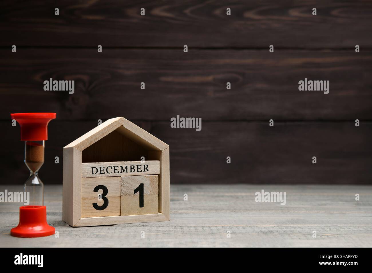 Weihnachtsschmuck auf Holzboden: Holzwürfel mit den Zahlen Dezember 31, rote Sanduhr. Selektiver Fokus Stockfoto