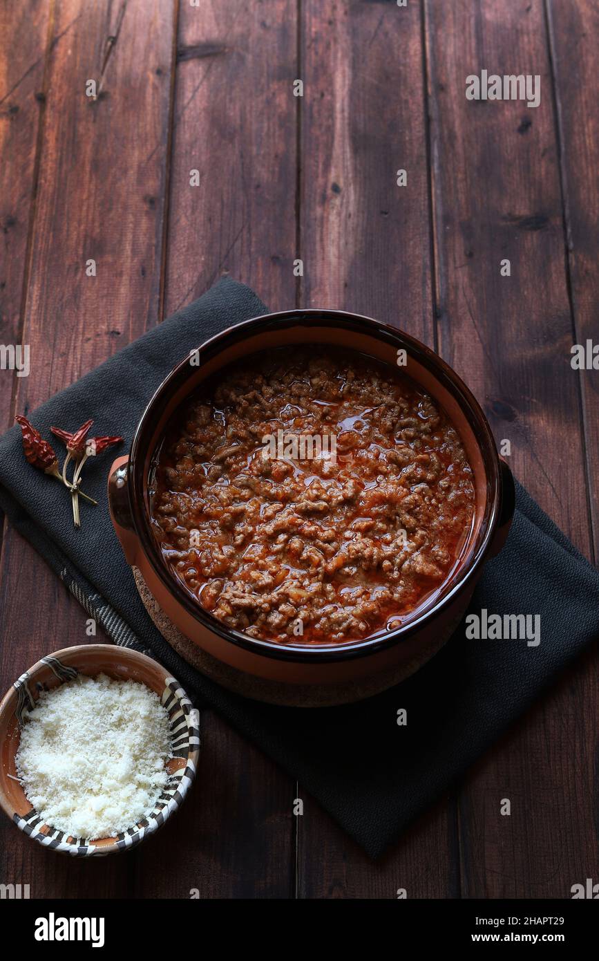 Hausgemachte Bolognese- oder ragù-Sauce in rustikaler Schüssel, auf dunklem Holz serviert. Direkt darüber. Stockfoto