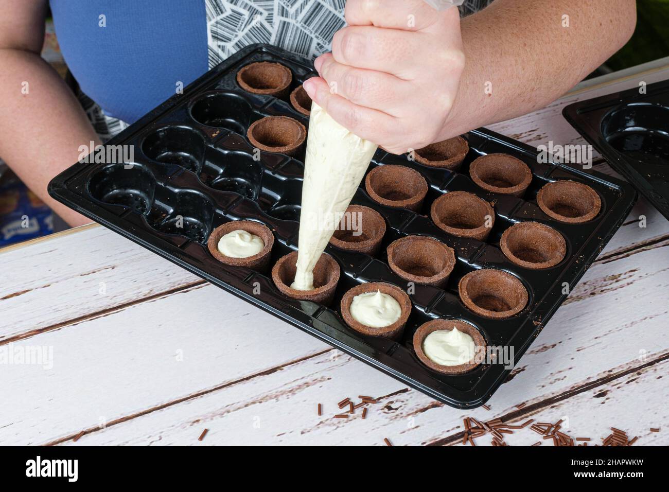 Selektiver Fokus. Konditorfüllung mit weißen Schokoladen-Ganache Mini-Schokoladen-Törtchen. Stockfoto