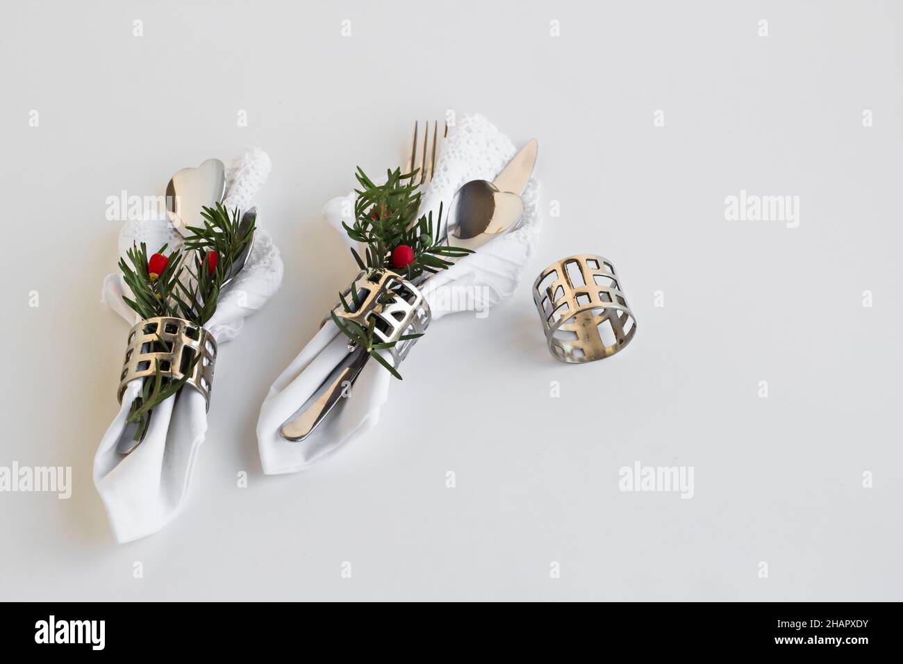Weisse Stoff weihnachtsservietten und weihnachtsdekorationen in Metall Serviettenring auf weißer Oberfläche mit Kopierraum Stockfoto