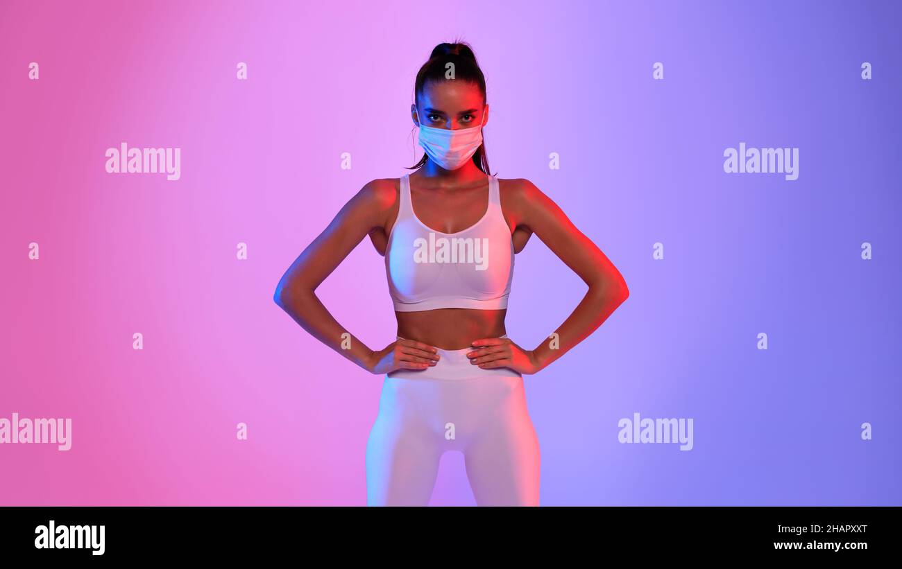 Sportliche Junge Dame Trägt Gesichtsmaske Auf Neonhintergrund Stehend Stockfoto