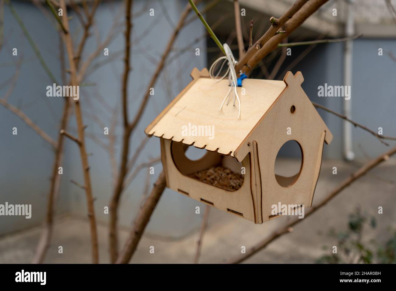 Hängendes kleines dekoratives gelbes Vogelhaus in der natürlichen grünen Umgebung. Leeres Holzhaus im Freien für Vögel beim Baumbrunch. Stockfoto